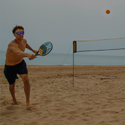 Um homem jogando beach tennis na praia.
